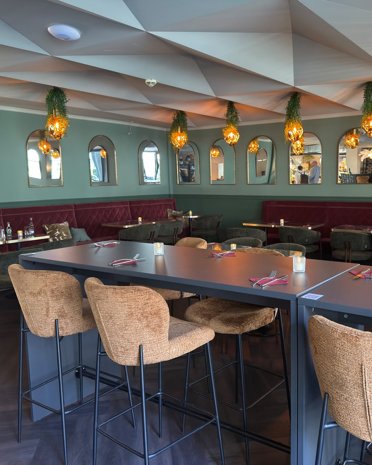 Innenraum des Bistros mit Marmortischen und gruenen Bänken